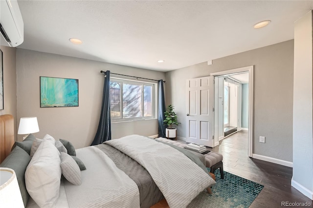 bedroom with an AC wall unit and dark hardwood / wood-style floors