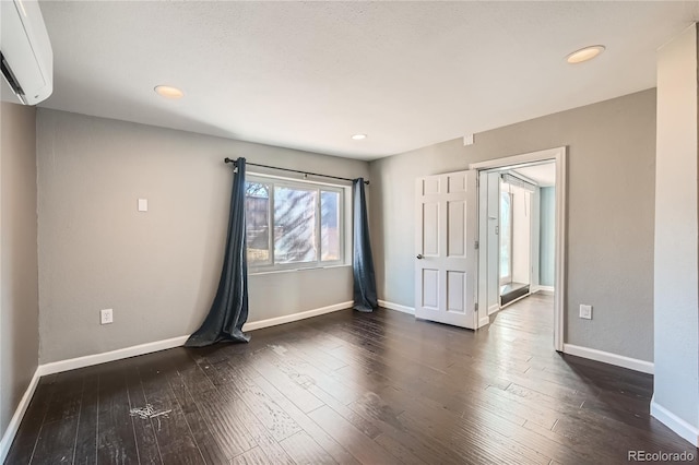 spare room featuring dark hardwood / wood-style floors and an AC wall unit