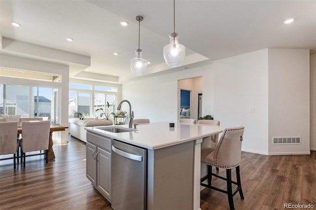 kitchen featuring pendant lighting, sink, dishwasher, a raised ceiling, and dark wood-type flooring