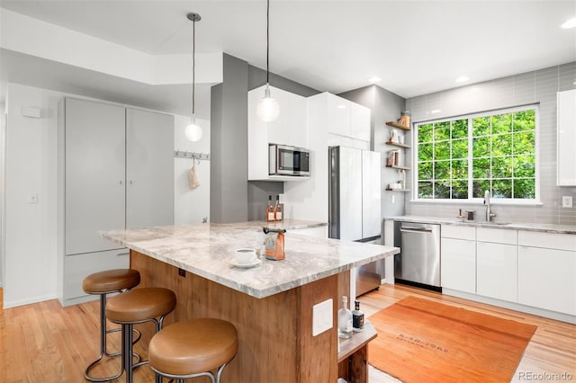 1947 King St, Denver, CO 80204 - kitchen with appliances with stainless steel finishes, open shelves, a breakfast bar area, modern cabinets, and a sink