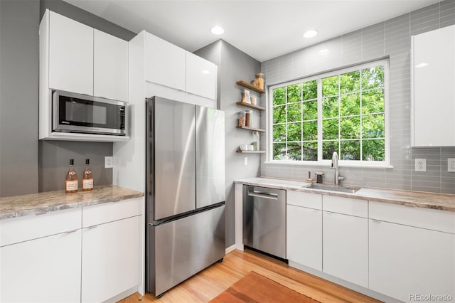 1947 King St, Denver, CO 80204 - kitchen with stainless steel appliances, a sink, tasteful backsplash, light wood-style flooring, and white cabinetry