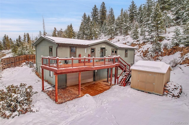 snow covered back of property with a deck and a garage