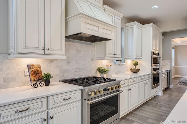 kitchen with light wood-type flooring, custom range hood, stainless steel range, and white cabinetry