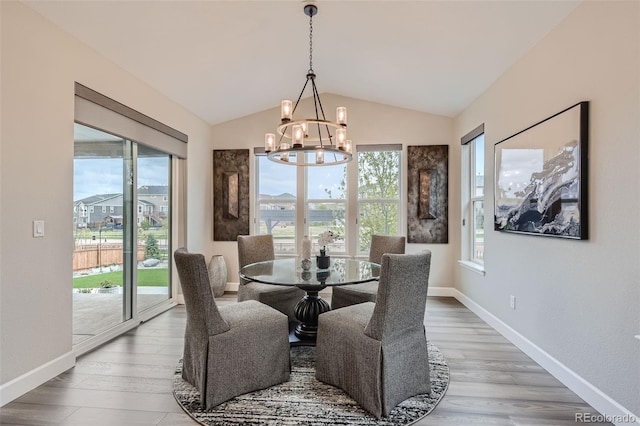 dining room featuring a chandelier, light hardwood / wood-style floors, and vaulted ceiling