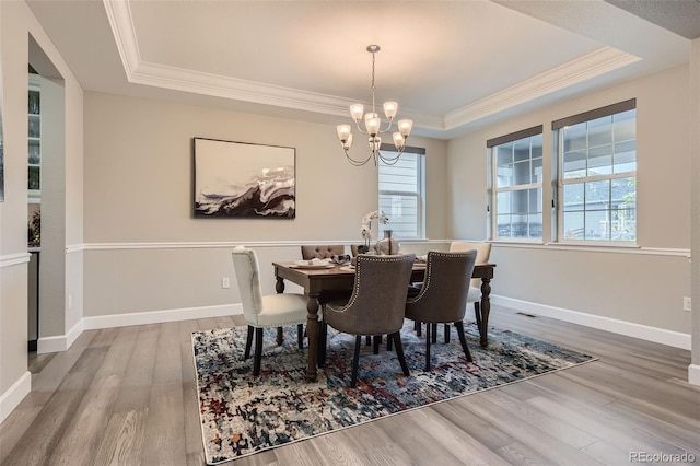 dining room featuring hardwood / wood-style floors, a tray ceiling, plenty of natural light, and a notable chandelier