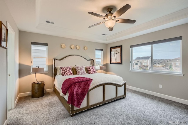 carpeted bedroom with a tray ceiling and ceiling fan