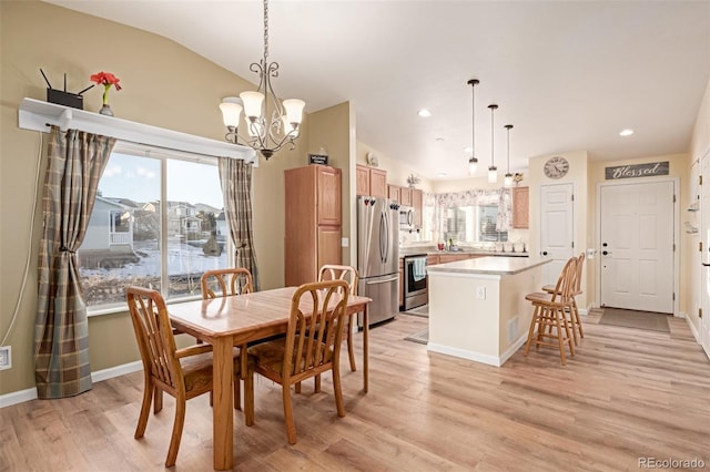 dining area featuring light hardwood / wood-style floors, a wealth of natural light, lofted ceiling, and an inviting chandelier