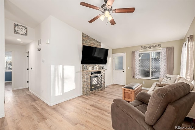 living room with light wood-type flooring, ceiling fan, lofted ceiling, and a fireplace