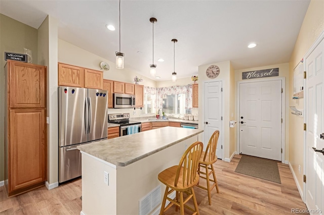 kitchen featuring pendant lighting, appliances with stainless steel finishes, a kitchen island, sink, and vaulted ceiling