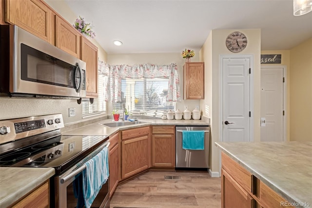 kitchen with stainless steel appliances, light hardwood / wood-style flooring, and sink