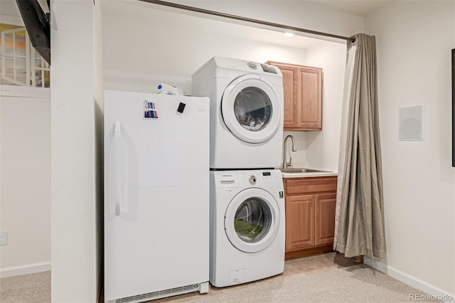 clothes washing area with a sink, baseboards, light colored carpet, and stacked washer and clothes dryer