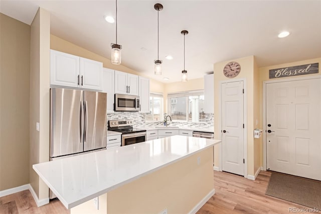 kitchen with light wood-type flooring, stainless steel appliances, decorative backsplash, and white cabinetry