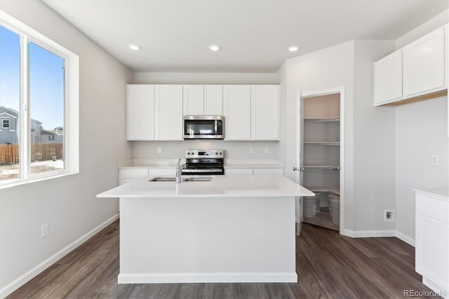 kitchen with stainless steel appliances, white cabinets, light countertops, and baseboards