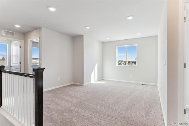 empty room featuring carpet floors, visible vents, and baseboards