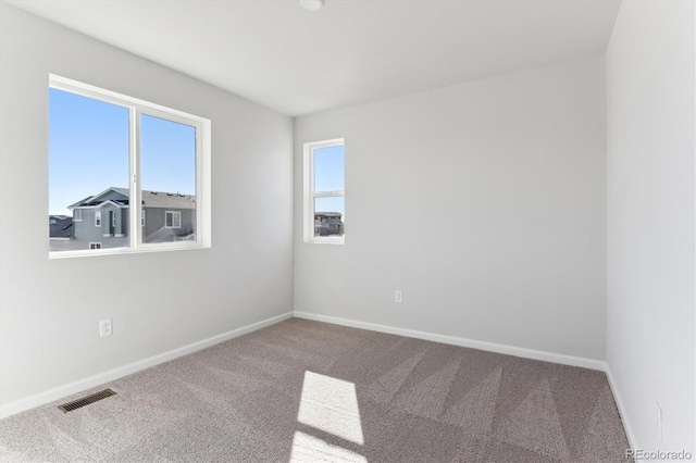 carpeted spare room featuring visible vents and baseboards