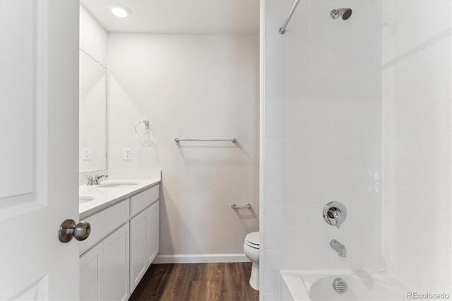 full bath featuring double vanity, toilet, a sink, shower / tub combination, and wood finished floors