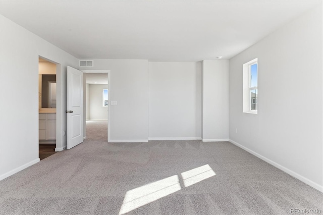 empty room with carpet flooring, visible vents, and baseboards