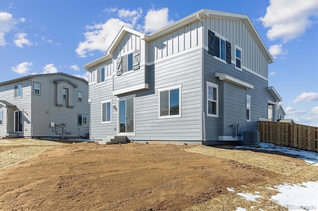 rear view of house featuring central AC unit, board and batten siding, and fence