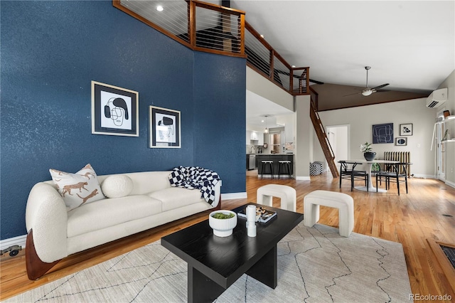 living room featuring a wall mounted AC, wood finished floors, a ceiling fan, and lofted ceiling