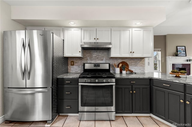 kitchen with under cabinet range hood, light stone counters, white cabinets, and stainless steel appliances