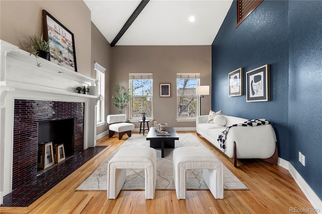 living area featuring wood finished floors, high vaulted ceiling, a fireplace, and baseboards