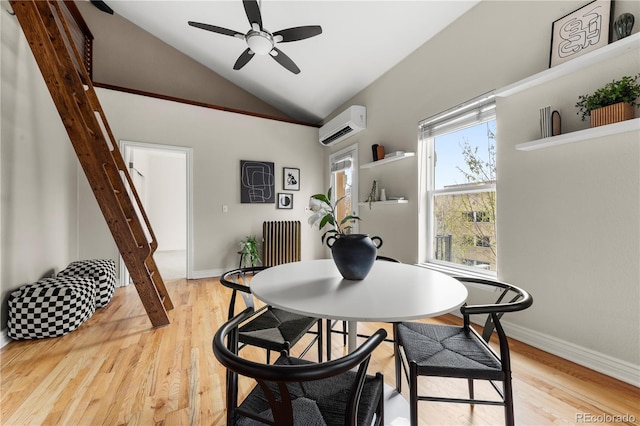 dining room featuring ceiling fan, light wood finished floors, vaulted ceiling, and a wall unit AC