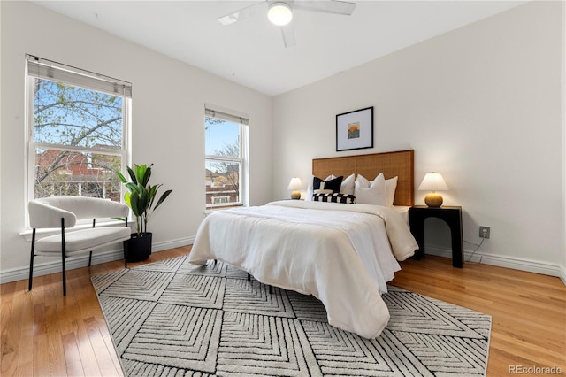 bedroom with light wood finished floors, baseboards, and a ceiling fan