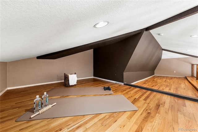 additional living space featuring wood finished floors, lofted ceiling with beams, and a textured ceiling