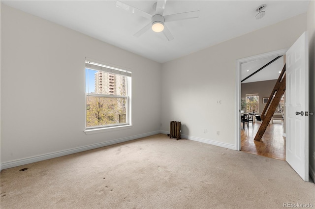 carpeted empty room with a healthy amount of sunlight, ceiling fan, and baseboards