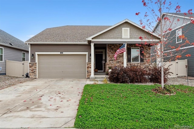 view of front of house with an attached garage, fence, concrete driveway, stone siding, and a gate