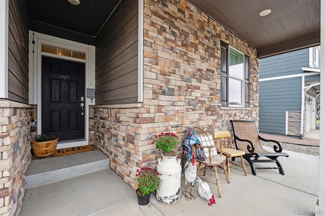 entrance to property featuring stone siding and a porch