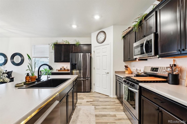 kitchen with recessed lighting, light countertops, appliances with stainless steel finishes, a sink, and light wood-type flooring