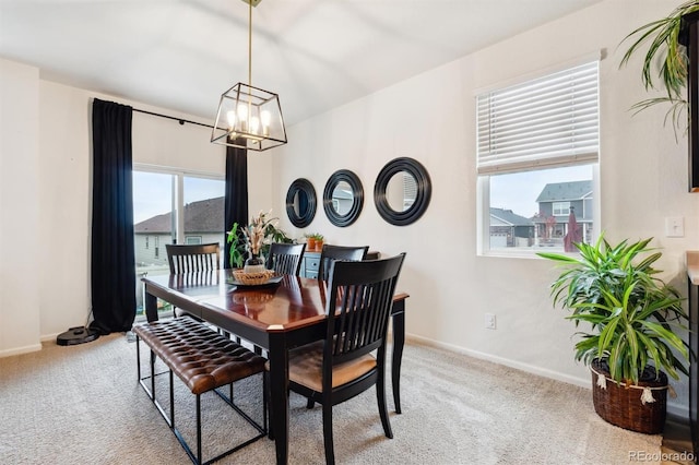 dining space featuring baseboards, a notable chandelier, and light colored carpet