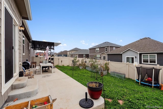 view of yard featuring a trampoline, a patio, a fenced backyard, a residential view, and a garden