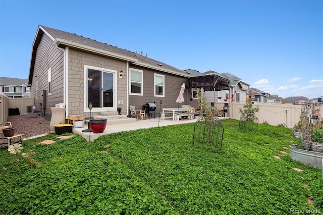 back of property with a yard, a patio, central air condition unit, entry steps, and a fenced backyard