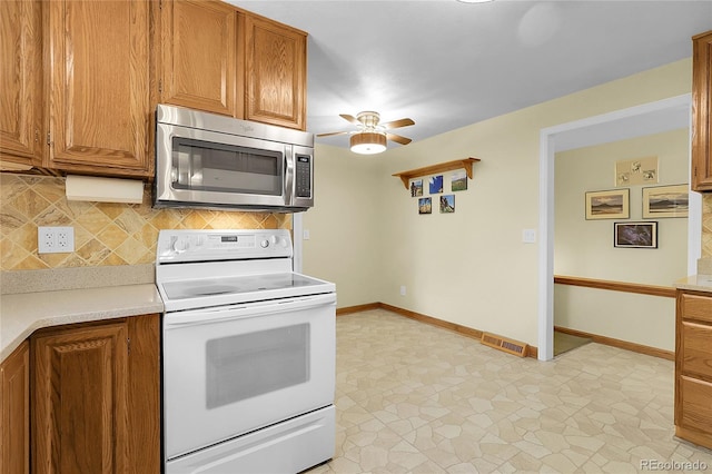 1091 E Pinewood Ave, Centennial, CO 80121 - kitchen with stainless steel microwave, white electric range, backsplash, light countertops, and brown cabinets
