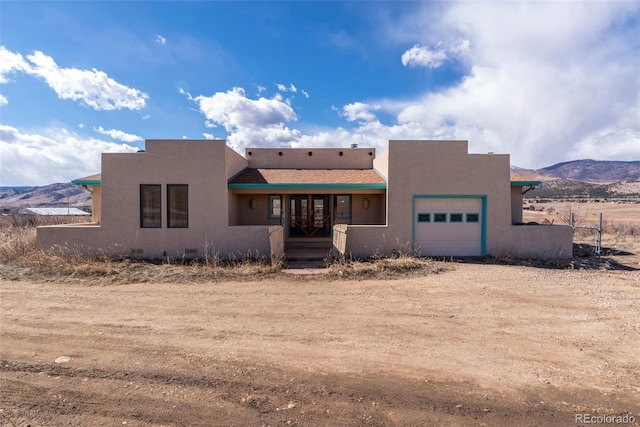 view of front of house featuring an attached garage, a mountain view, and stucco siding