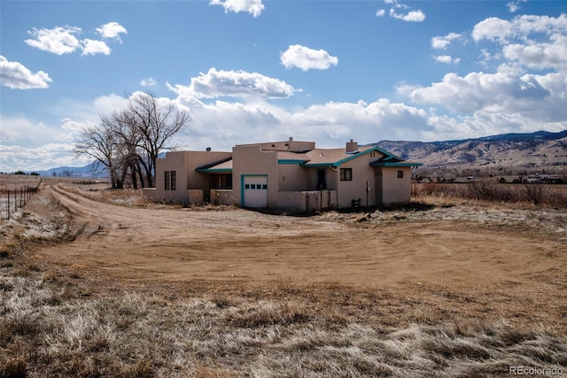 rear view of house with a garage, a mountain view, and stucco siding