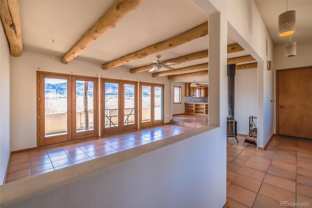 kitchen featuring baseboards, a ceiling fan, beamed ceiling, a wood stove, and tile patterned flooring