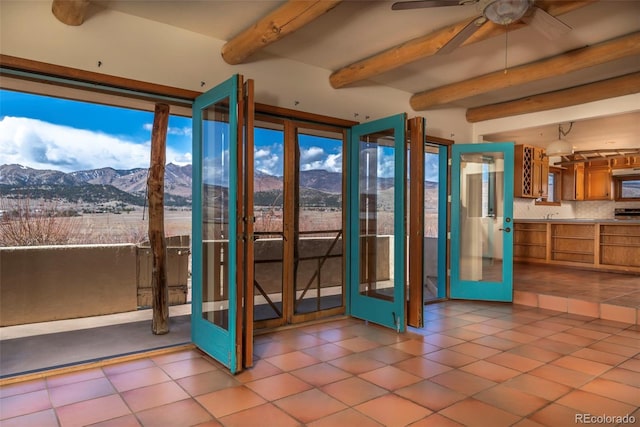 interior space featuring french doors, a mountain view, beamed ceiling, and light tile patterned floors