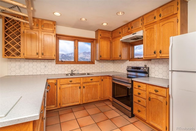 kitchen featuring freestanding refrigerator, stainless steel range with electric cooktop, under cabinet range hood, a sink, and light tile patterned flooring