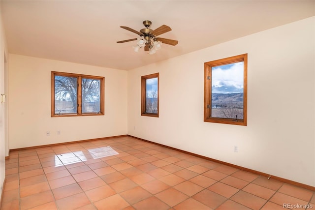 empty room with light tile patterned floors, baseboards, and a wealth of natural light