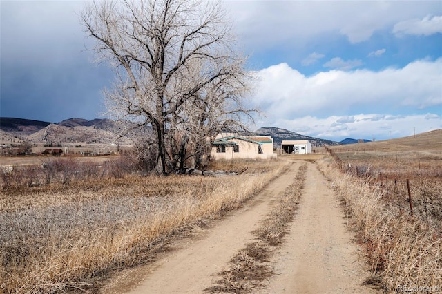 view of road with driveway, a mountain view, and a rural view