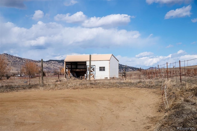 exterior space featuring an outbuilding, a rural view, an outdoor structure, and a mountain view