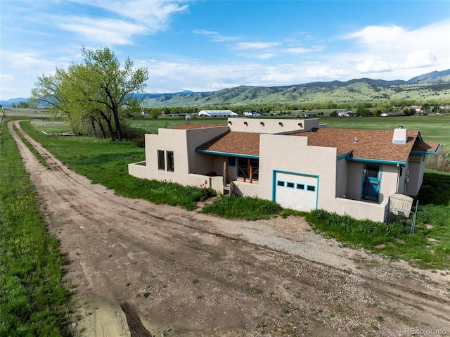 8602 N 39th St, Longmont, CO 80503 - view of front of property featuring a garage, a mountain view, driveway, stucco siding, and a view of rural / pastoral area