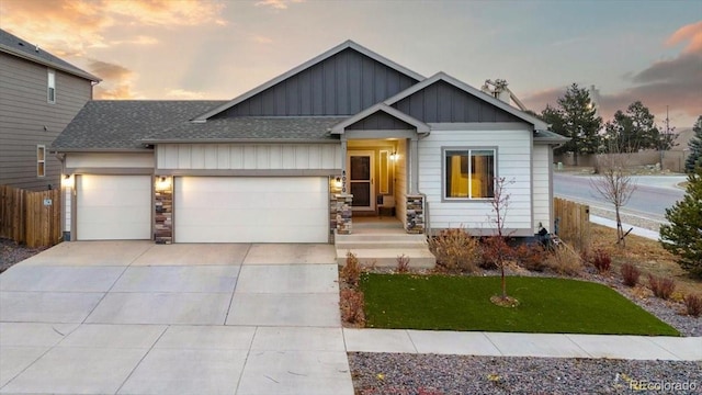 view of front of property featuring roof with shingles, concrete driveway, board and batten siding, fence, and a garage