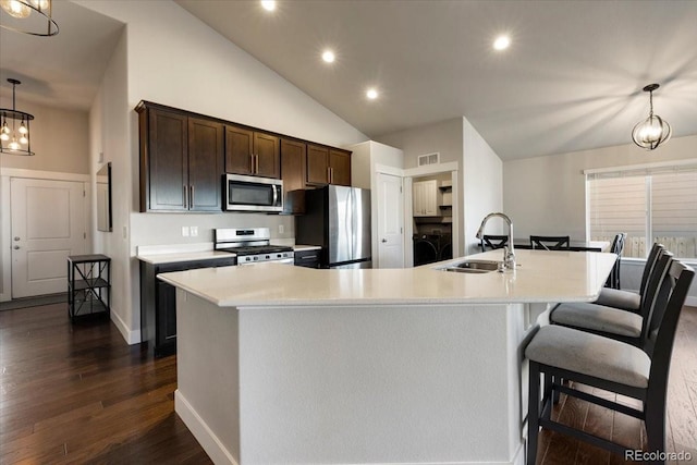 kitchen with dark wood-style flooring, stainless steel appliances, light countertops, a sink, and dark brown cabinets