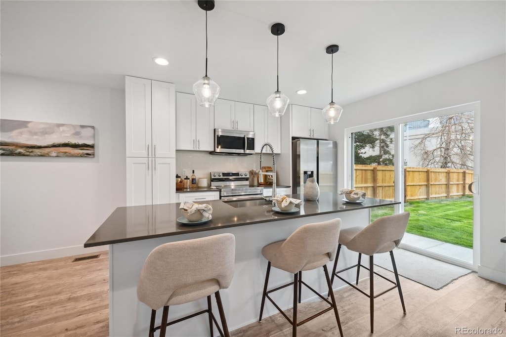 kitchen with a breakfast bar area, stainless steel appliances, white cabinetry, and sink