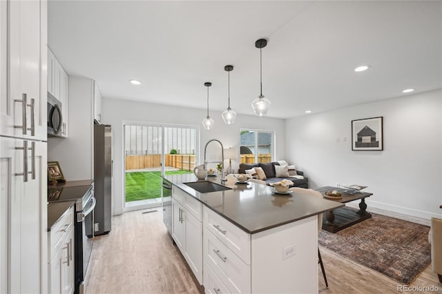 kitchen featuring a kitchen breakfast bar, white cabinetry, a center island with sink, and stainless steel appliances