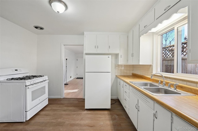 kitchen featuring sink, white cabinets, decorative backsplash, light hardwood / wood-style floors, and white appliances